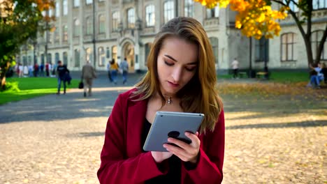 Schöne-junge-Mädchen,-Student-Surfen,-Messaging-auf-dem-Tablet,-wird-frustriert-und-dann-amüsiert,-außerhalb-der-Universität