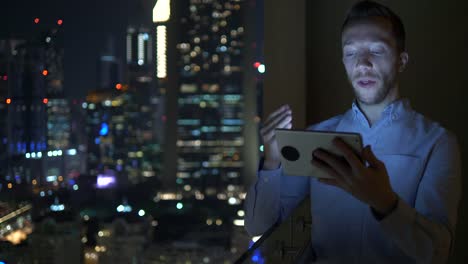 Young-man-using-tablet-to-speak-and-communicate-with-skyscraper-view-background