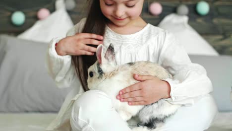 Chica-sentada-junto-a-la-cesta-de-Pascua-y-acariciando-el-conejo