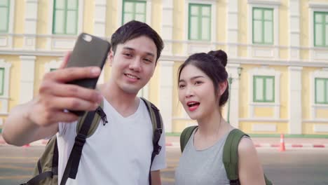 Asian-blogger-couple-travel-in-Bangkok,-Thailand,-sweet-couple-using-mobile-phone-make-vlog-and-live-in-social-media-while-spending-sweet-time-in-holiday-trip.-Couple-travel-in-city-concept.