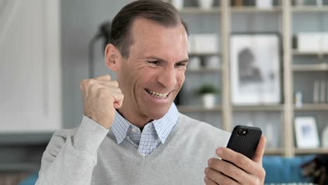 Excited-Man-Enjoying-Success-while-Using-Smartphone