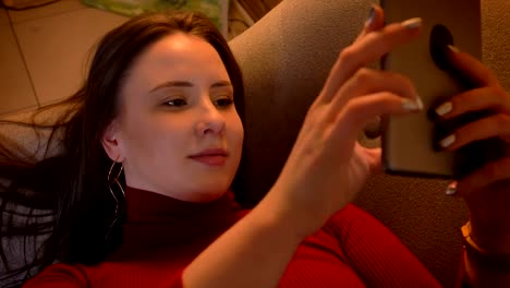 Closeup-shoot-of-young-pretty-caucasian-female-typing-on-the-tablet-while-lying-on-the-couch-indoors