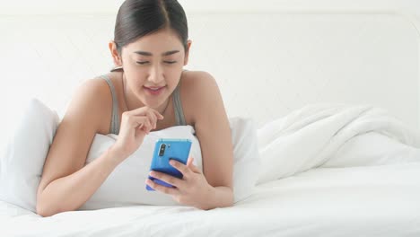 Asiatische-Frau-typisiert-App-Social-Media-im-Smartphone-im-Bettzimmer.-Konzept-von-Technik,-Kommunikation-und-Einkaufen.