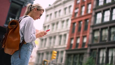 Attraktive-Millennial-Frau-Reisende-in-stilvollen-Kleidung-machen-Online-Buchung-des-Hotels-über-Handy-App-verbunden-mit-4g-Wireless-während-Sightseeing-rund-um-die-Straßen-der-Stadt