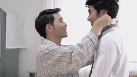 Asian-couple-gay-helping-tie-a-necktie-and-dress-to-work-in-morning-at-home.-Gay-boy-happy-emotion-and-hug-love-anniversary-together.-Concept-of-lifestyle,-family,-gay-and-bisexual.