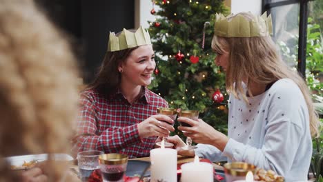 Pareja-gay-mujer-sentada-alrededor-de-la-mesa-para-la-cena-de-Navidad-susurrando-y-haciendo-tostadas