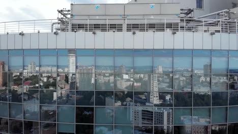 Skyscraper-roof-reveal-with-windows-reflections-of-city-and-sky