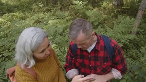 Älteres-Familienpaar-mit-modernen-Gadgets-im-Wald