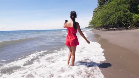 Viaje-mujer-vlogger-caminando-en-la-playa-y-la-grabación-vlog-en-el-teléfono-inteligente.