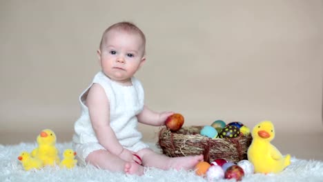 Lindo-niño-pequeño-niño,-jugando-con-huevos-de-pascua-de-colores-y-patos-decorativos-pequeños,-tiro-aislado,-fondo-beige