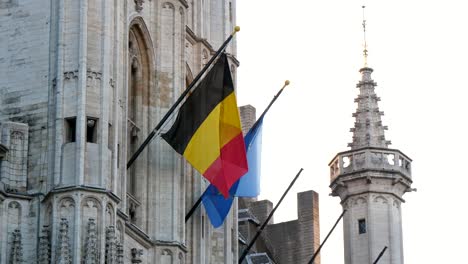 Hohes-historisches-Gebäude-mit-aufsteigenden-Flaggen-Belgiens-und-der-Europäischen-Union-in-slo-mo