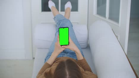 Phone-with-Green-Screen-and-Chroma-Key-Closeup.-Chromakey-Mockup-with-Tracking-Markers-and-Alpha-Matte.-POV-is-Vertical-Template-of-Device-in-Modern-House-Closeup.-Scroll-Up-Online-News-at-Cellphone