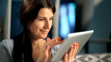 Woman-using-digital-tablet-at-home-sitting-on-sofa