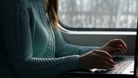 Weibliche-Hände-Tippen-auf-Tastatur-von-Laptop-im-Zug.-Frau-während-der-Eisenbahn-unterwegs-mit-Freunden-chatten.-Junges-Mädchen-mit-Notebook.-Arm-drucken-Sie-eine-Nachricht.-Nahaufnahme