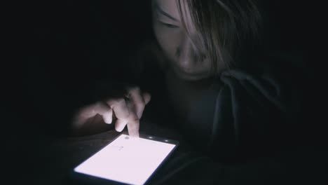 Woman-using-cellphone-in-bed-at-night