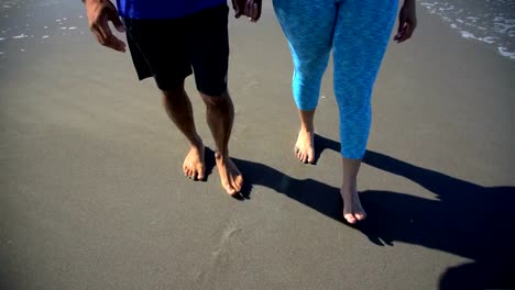 Multi-ethnic-couple-walking-holding-hands-on-beach