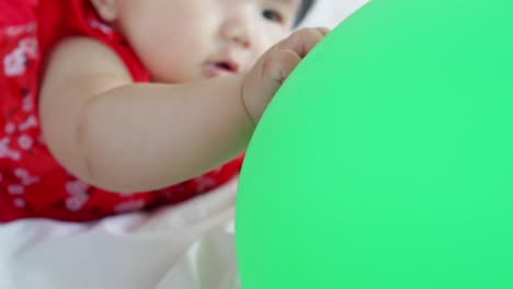 Cute-asian-little-baby-girl-having-fun-to-try-to-catch-and-play-with-balloon-in-slow-motion-shot