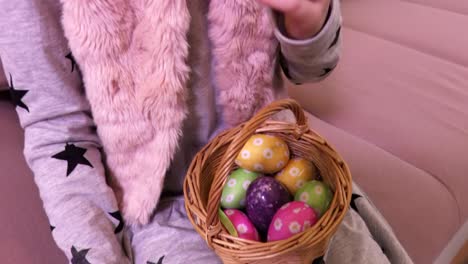 Little-girl-with-Easter-eggs-in-basket-and-carrot-on-sofa