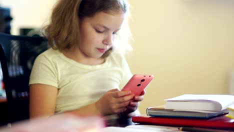 The-schoolgirl-closes-the-book-and-gaily-takes-her-pink-mobile-phone.-Communication-in-social-networks.-Problems-of-education.-Internet-addiction