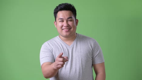 Young-handsome-overweight-Asian-man-against-green-background