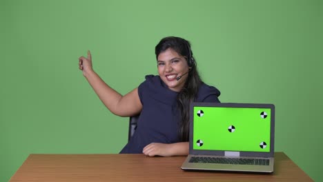 Young-overweight-beautiful-Indian-businesswoman-against-green-background