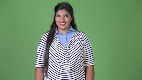 Young-overweight-beautiful-Indian-businesswoman-against-green-background