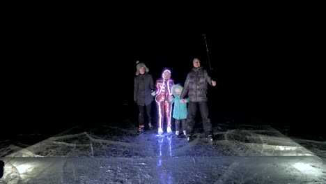 Family-is-ice-skating-night,-make-selfie.-Mother,-father,-daughter-and-son-riding-together-on-ice-in-cracks.-Outdoor-winter-fun-for-athlete-nice-winter-weather.-People-on-ice-skates.