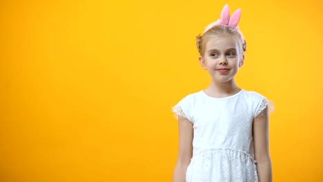 Cute-girl-in-white-dress-shaking-colored-pink-egg-on-yellow-background,-festival