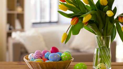 huevos-de-Pascua-en-cesta-y-tulipán-flores-en-casa