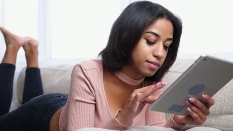 Teenage-girl-using-digital-tablet-on-sofa