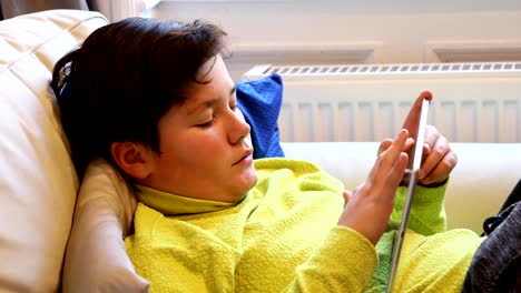 Child-lying-on-a-sofa-with-digital-tablet-computer