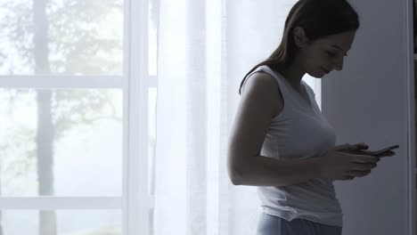 Mujer-caminando-en-la-habitación-y-conversando-con-su-teléfono