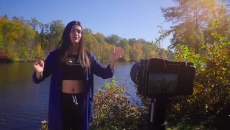 Blogging-young-woman-stand-next-to-camera-at-nature-talking-and-gesturing-and-smiling-slow-motion