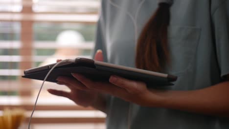 Cerrar-la-mano-de-la-mujer-joven-asiática-usando-la-tableta.-tecnología,-redes-sociales,-concepto-de-comunicación-en-casa.