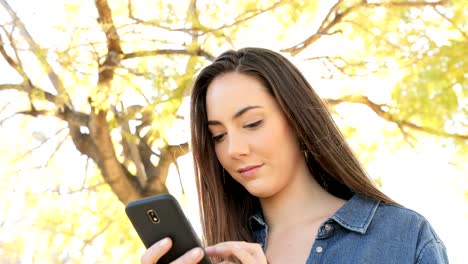 Seriöse-Frau-mit-Smartphone-in-einem-Park