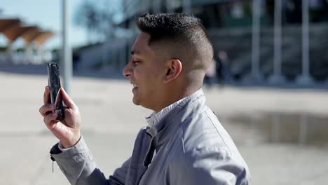 Sonriente-joven-que-tiene-videollamada-a-través-de-teléfono-móvil-roto.