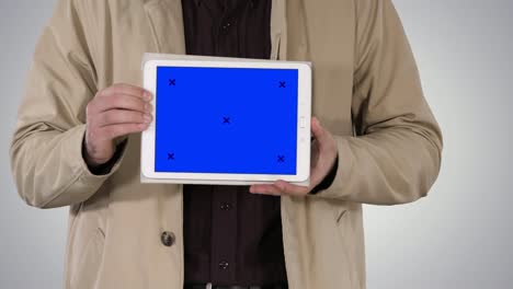 Male-hands-holding-tablet-with-blue-screen-mockup-on-gradient-background