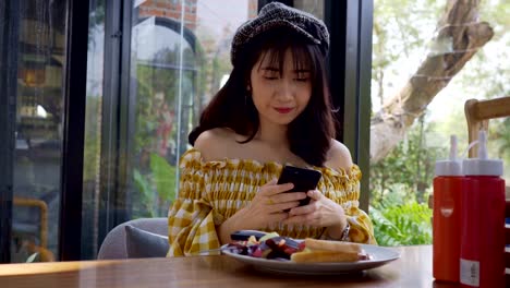 Asian-young-woman-taking-a-photo-of-breakfast-with-smartphone-social-media