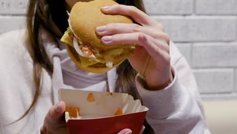 Mujer-comiendo-una-hamburguesa-con-gusto-y-deleite-en-la-cafetería.