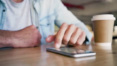 Hands-Of-man-Using-Mobile-Phone-On-Table