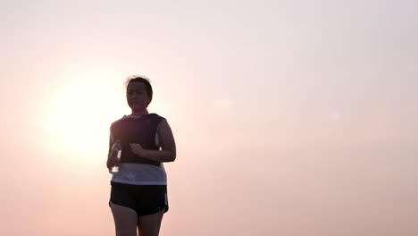 Übergewichtige-asiatische-Frauen-joggen-am-frühen-Morgen-im-Sonnenlicht-auf-der-Straße.-Konzept-des-Gewichtsverlustes-mit-Bewegung-für-die-Gesundheit.