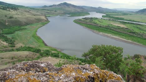 Sommer,-Tag,-Blick-vom-Hügel-über-den-Fluss-mit-einem-Felsen-im-Vordergrund