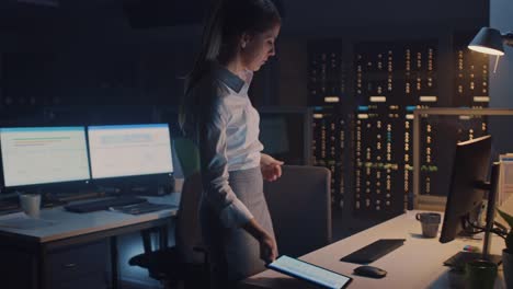 Following-Shot-of-Businesswoman-Walking-into-Corporate-Office-with-Digital-Tablet-Computer,-She-Takes-Her-Place-at-Desktop-Computer-and-Proceeds-Working-on-Important-Project