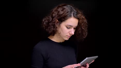 Seitenansicht-eines-jungen-kaukasischen-Weibchens,-das-das-Tablet-mit-Blick-auf-die-Kamera-benutzt-und-fröhlich-lacht