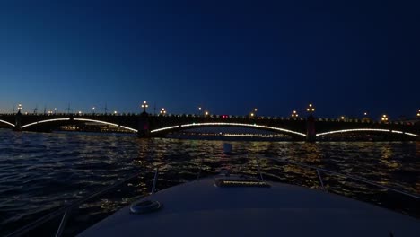 Center-of-St.-Petersburg,-Russia-at-night.-On-the-river-pass-passenger-boats.-The-ship-turns-on-the-water-and-floats-towards-the-bridge