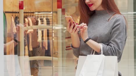 Mujer-sonriendo,-navegando-en-su-teléfono-inteligente-mientras-compra-en-el-centro-comercial