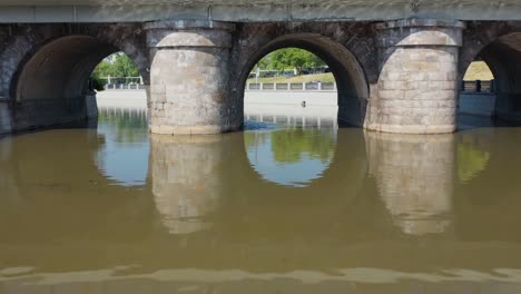 Volando-a-lo-largo-del-río-de-la-ciudad,-por-encima-y-debajo-del-antiguo-puente-de-piedra.