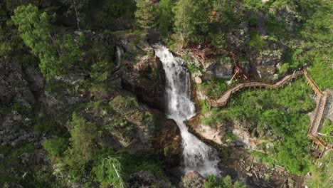 Drohne-fliegt-über-einen-grünen-Wald-mit-Wasserfall-im-Altai-Gebirge