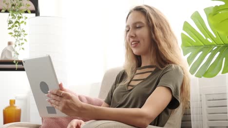 Teen-girl-video-chatting-using-digital-tablet-on-sofa