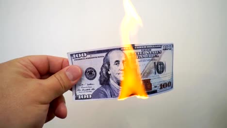 Hand-holding-a-burning-hundred-dollar-banknote